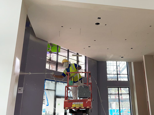 a commercial painting contractor uses an paint sprayer to paint the interior of an office building